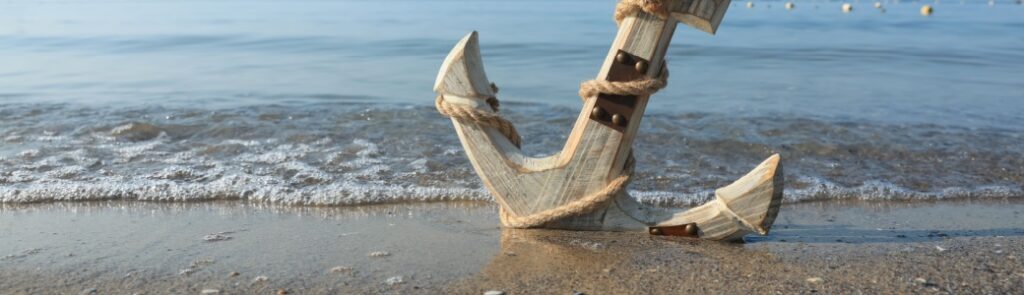 A wooden anchor on a beach.