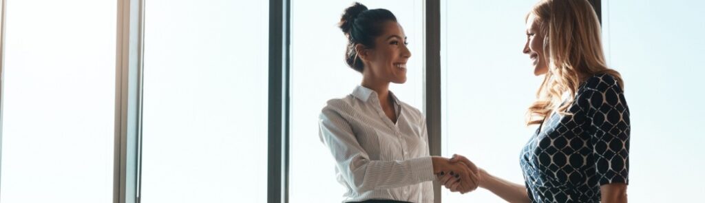 Two women shaking hands in an office.